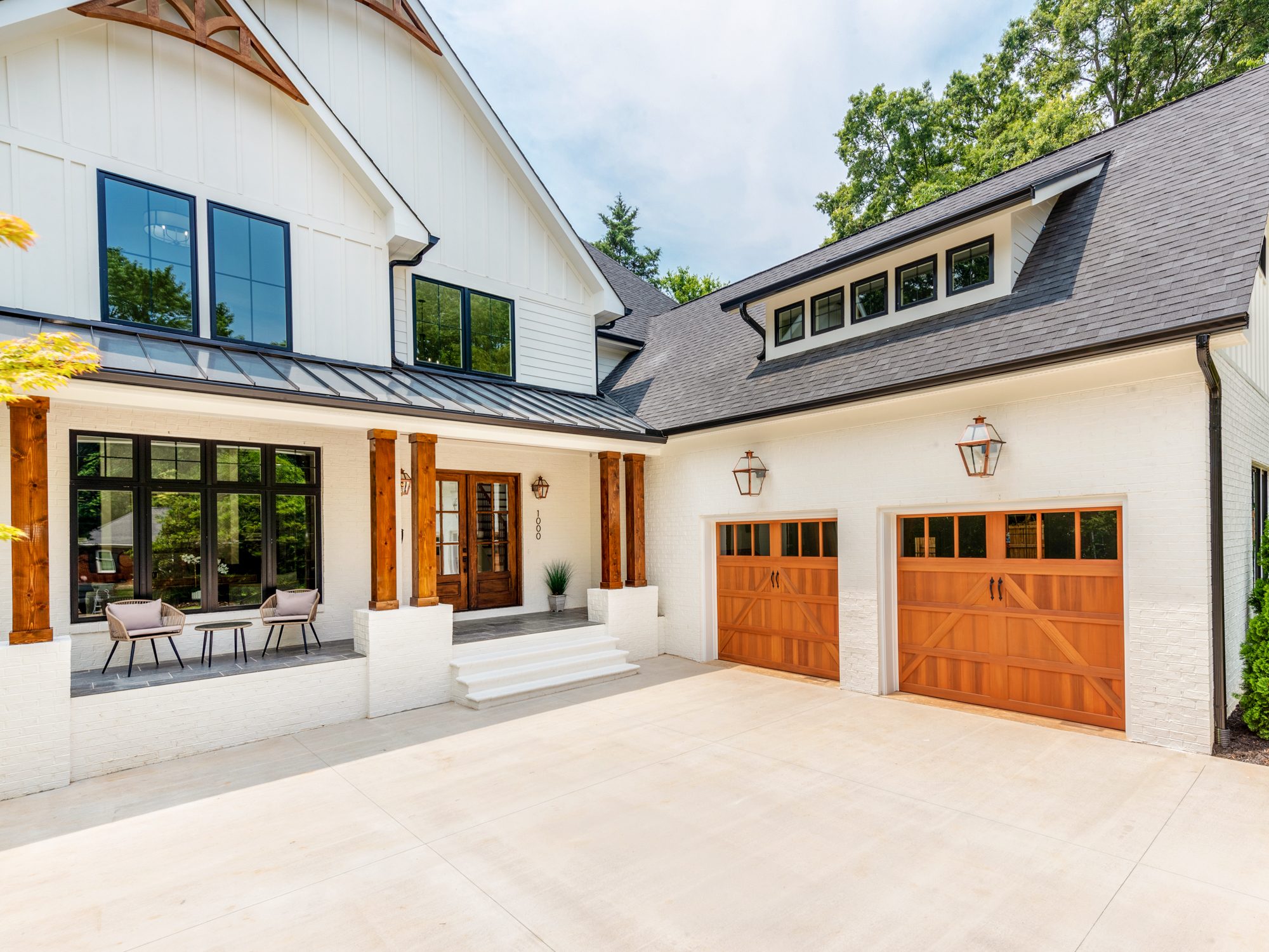 Architectural detail showing cedar gable brackets, standing-seam porch roof, and carriage-style garage doors — Brantham by Stillman Properties Charlotte NC