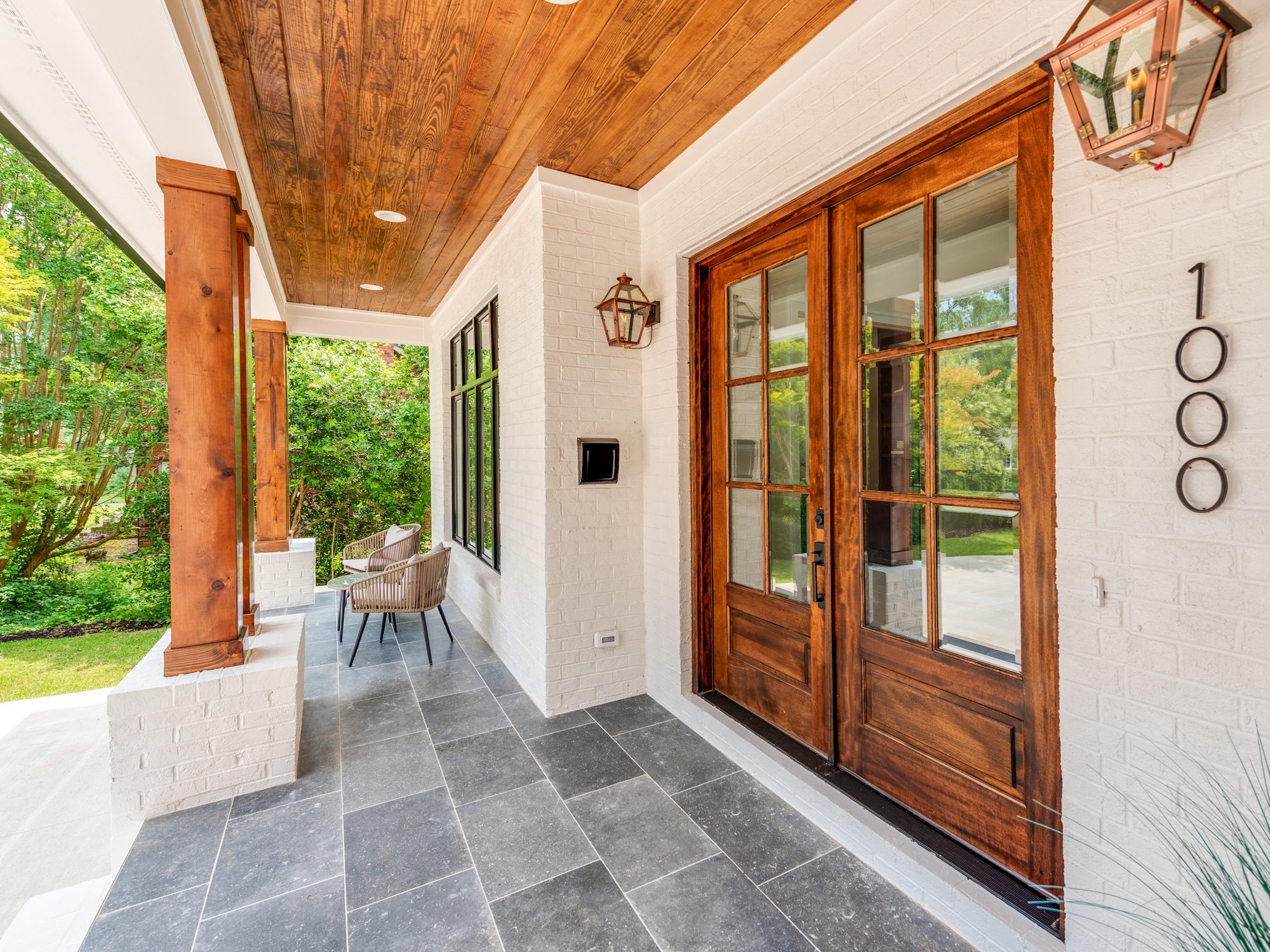 Front porch entry with cedar ceiling, copper lanterns, slate floor, and walnut double doors — Brantham by Stillman Properties Charlotte NC