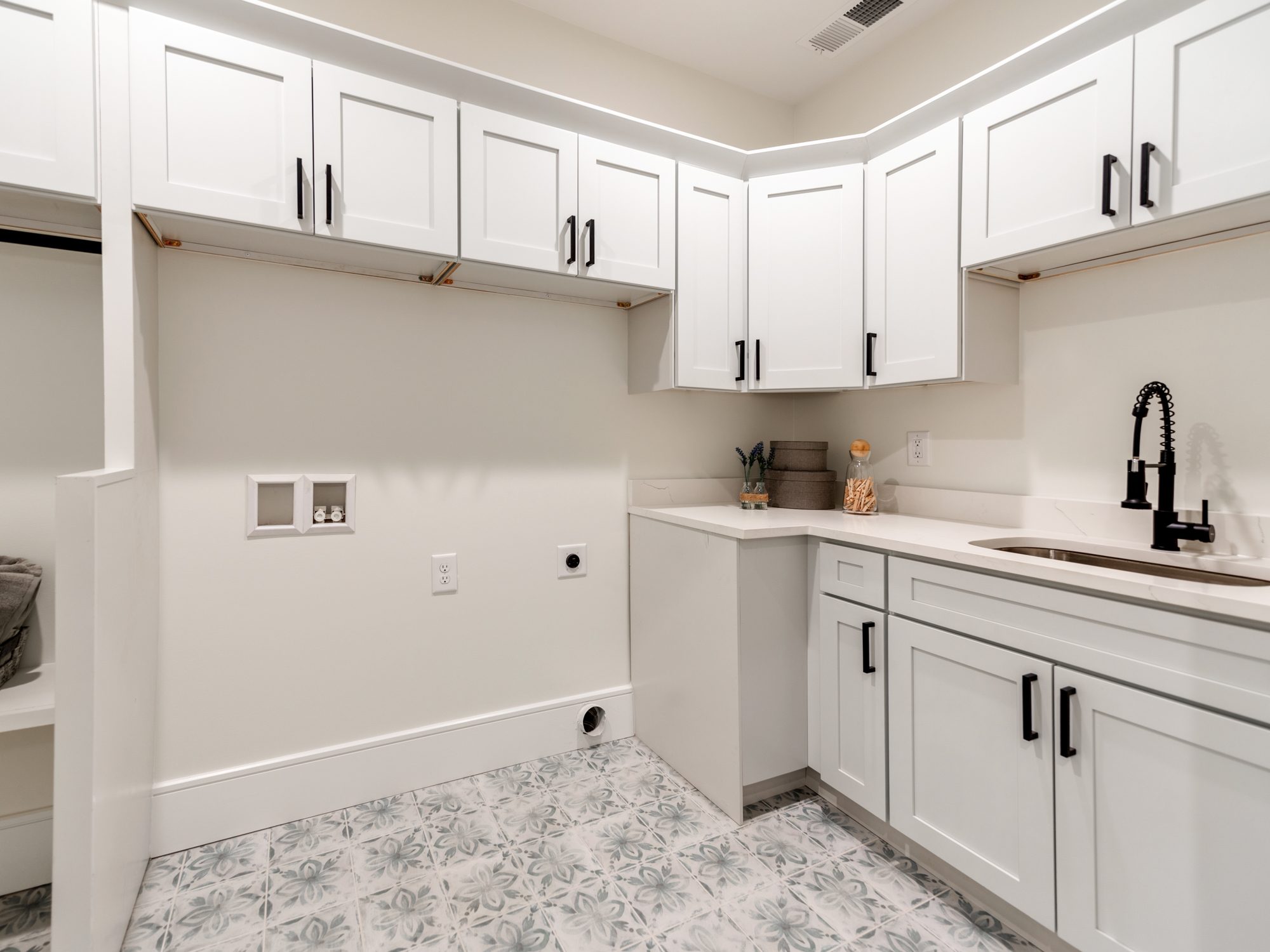Laundry room with white cabinetry, black hardware, and patterned tile floor — Brantham by Stillman Properties Charlotte NC