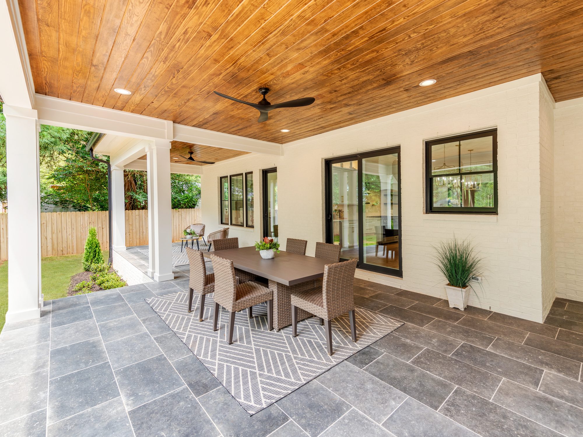 Outdoor dining area beneath the cedar-ceilinged covered porch — Brantham by Stillman Properties Charlotte NC