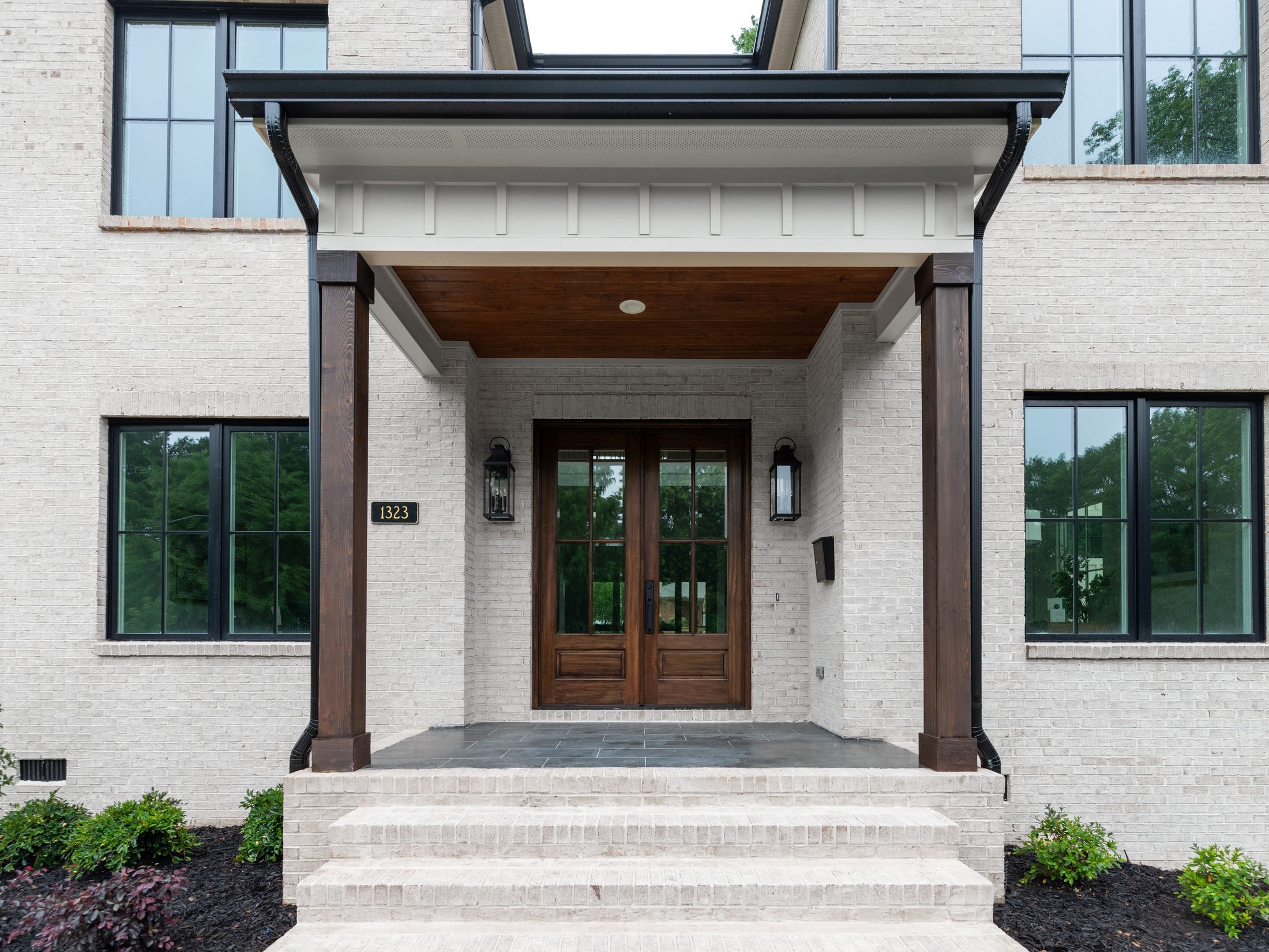 Front entry detail with cedar columns, cedar porch ceiling, black lanterns, and walnut double door — Bywood by Stillman Properties Charlotte NC