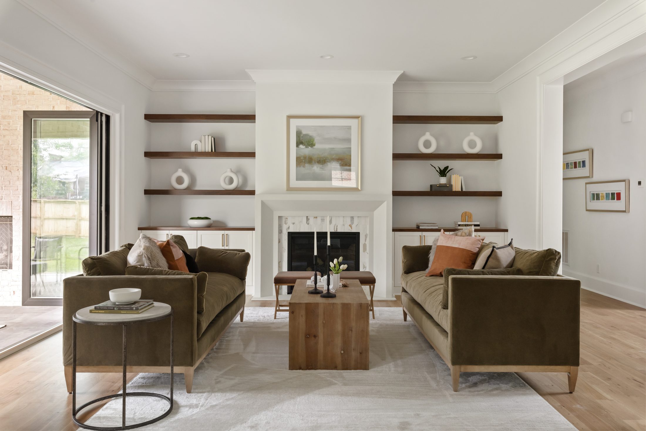 Great room with marble-surround fireplace flanked by walnut floating shelves and built-in cabinetry — Bywood by Stillman Properties Charlotte NC