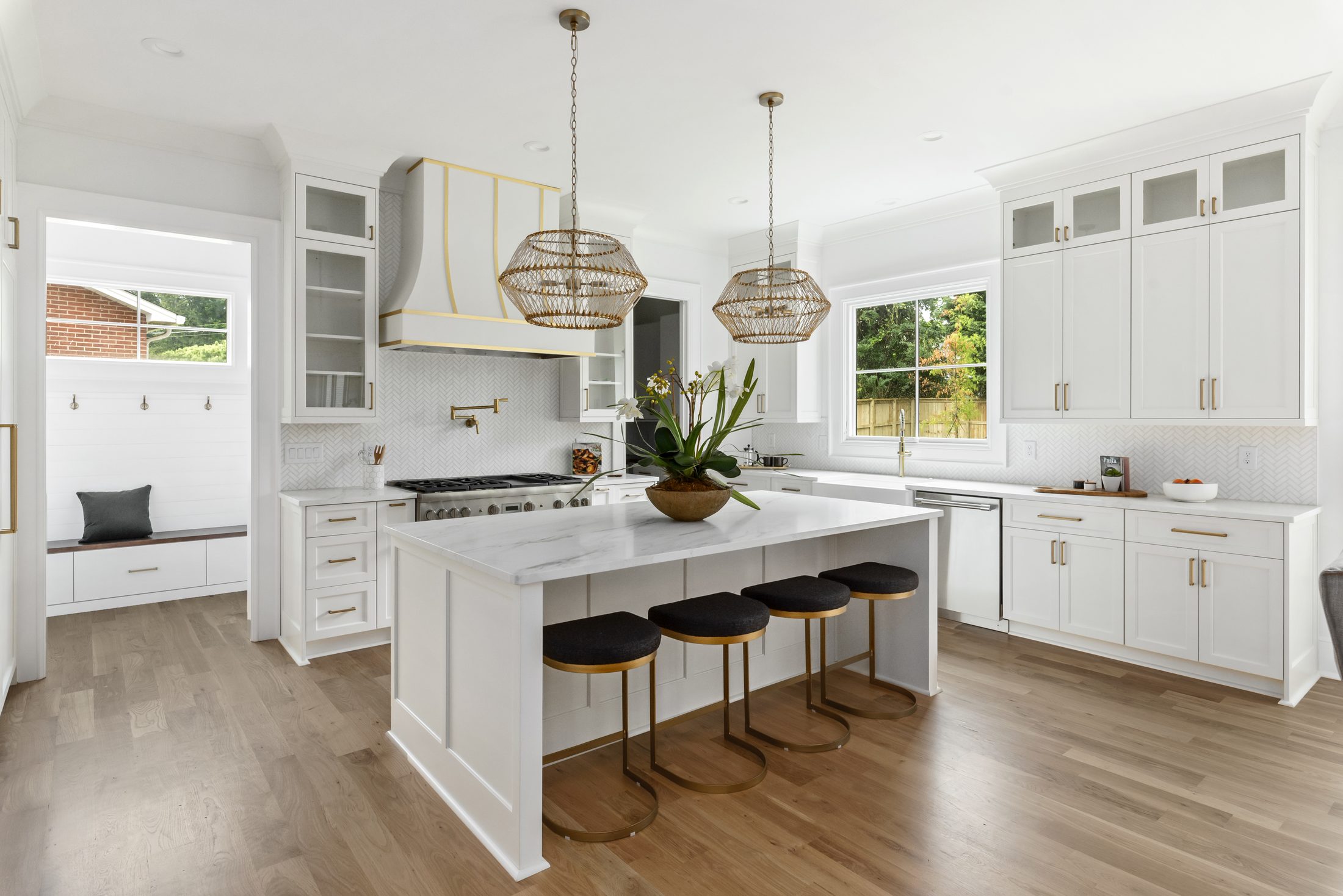 Chef's kitchen with oversized marble-look island, custom range hood, and woven pendants — Bywood by Stillman Properties Charlotte NC