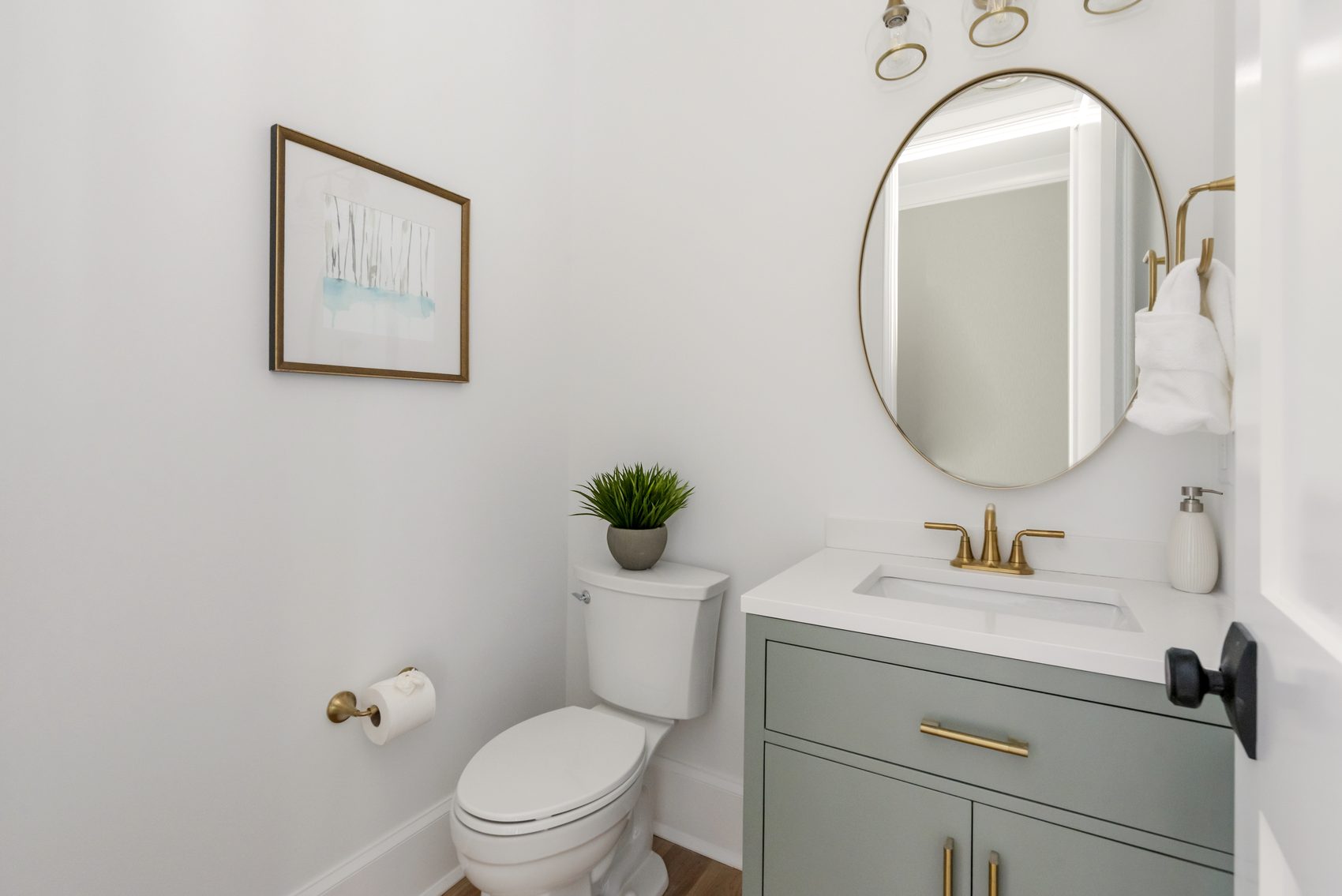 Designer powder bath with sage-green vanity, brass fixtures, and round mirror — Bywood by Stillman Properties Charlotte NC