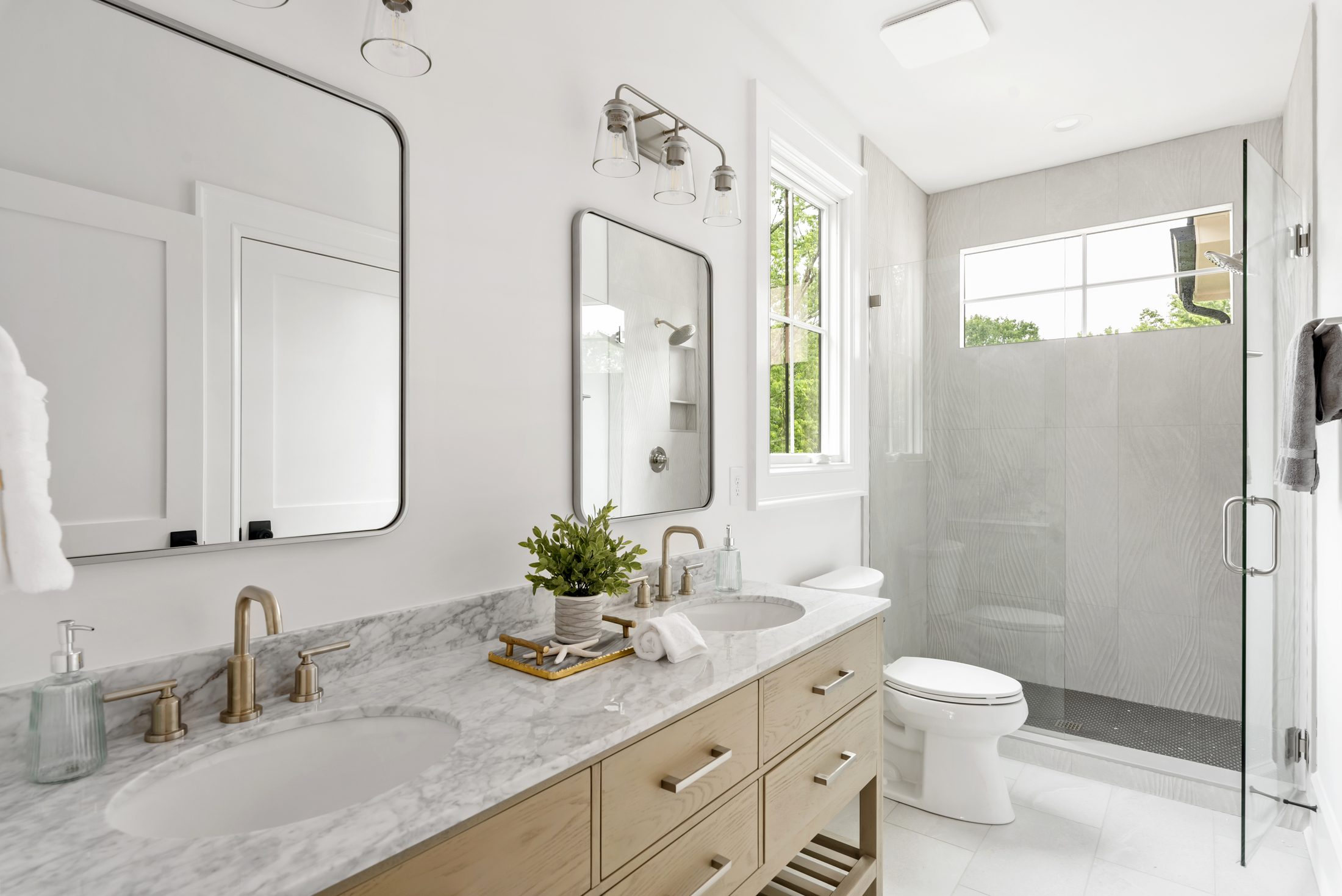Secondary bath with light wood double vanity, marble counter, and walk-in tile shower — Bywood by Stillman Properties Charlotte NC