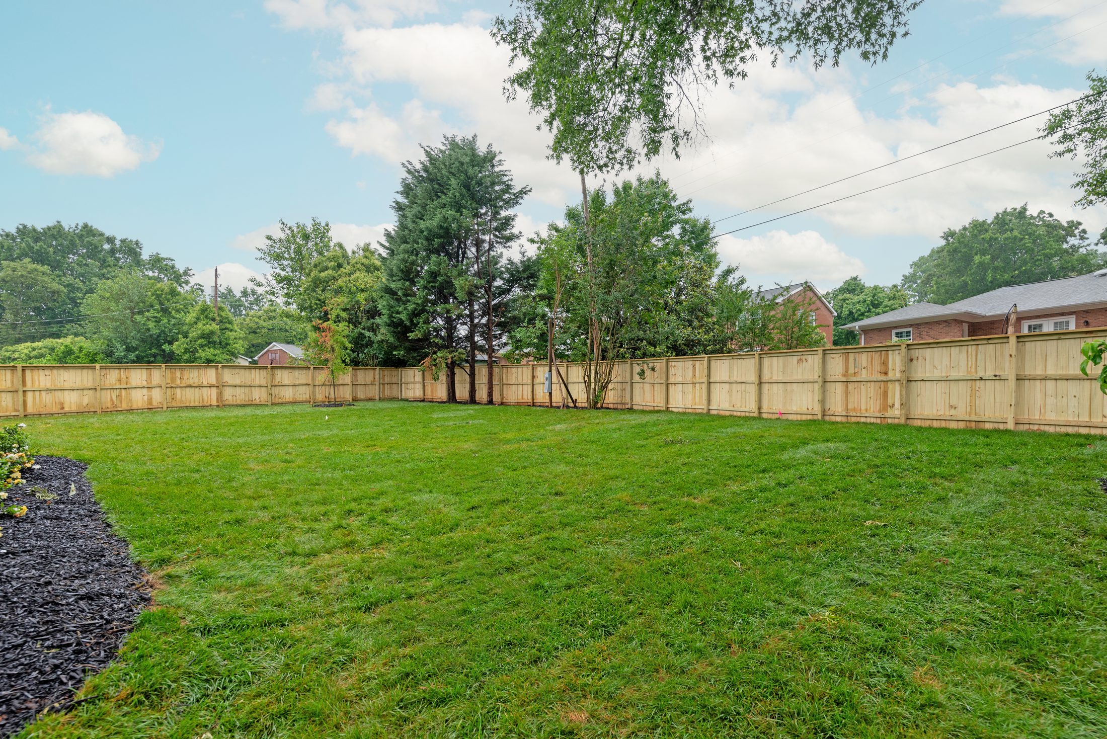 Wide rear-yard view of Bywood with fresh sod and landscaped beds — Stillman Properties Charlotte NC