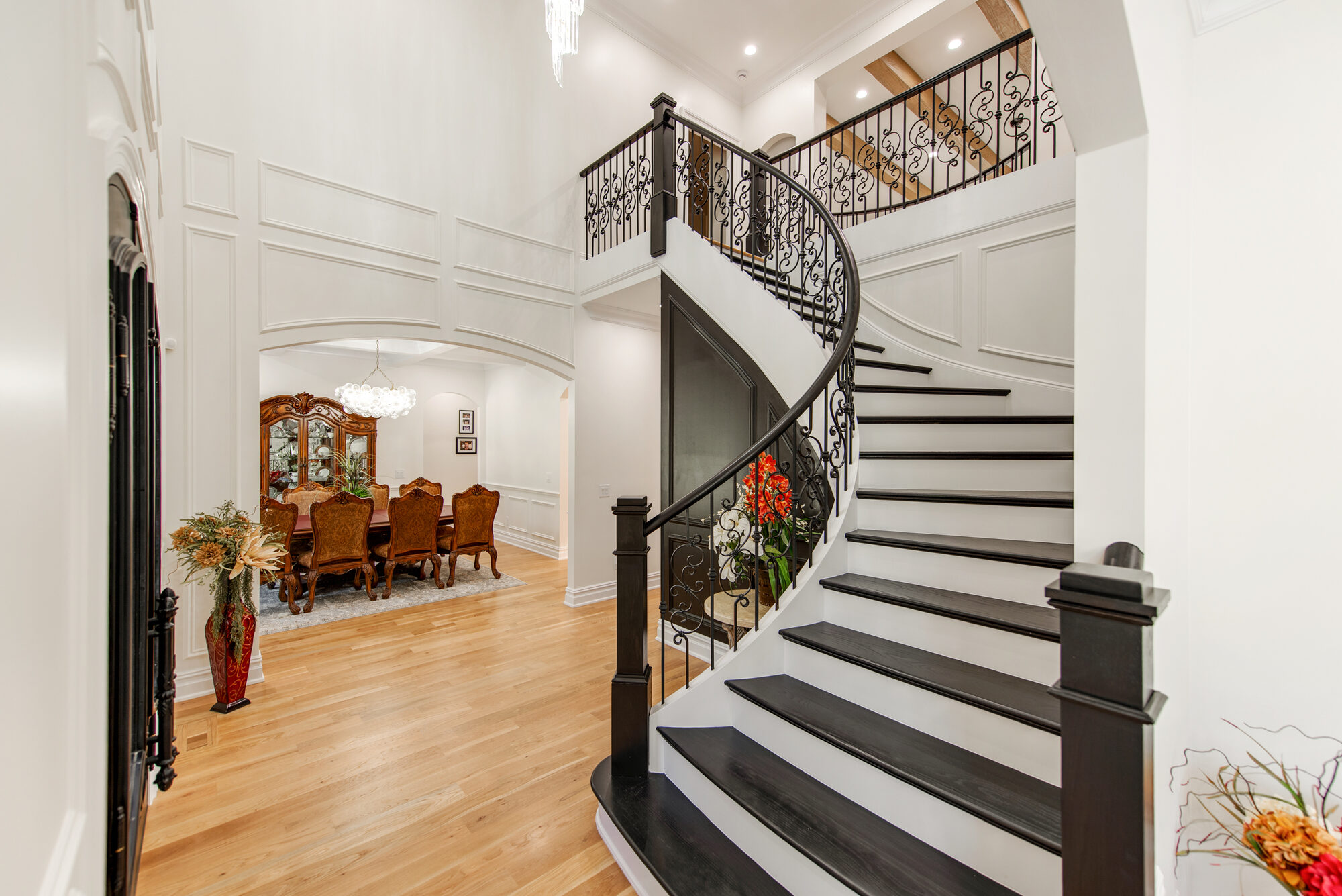 Foyer view toward the formal dining room with curved staircase and crystal chandelier — Coddle Creek by Stillman Properties Concord NC
