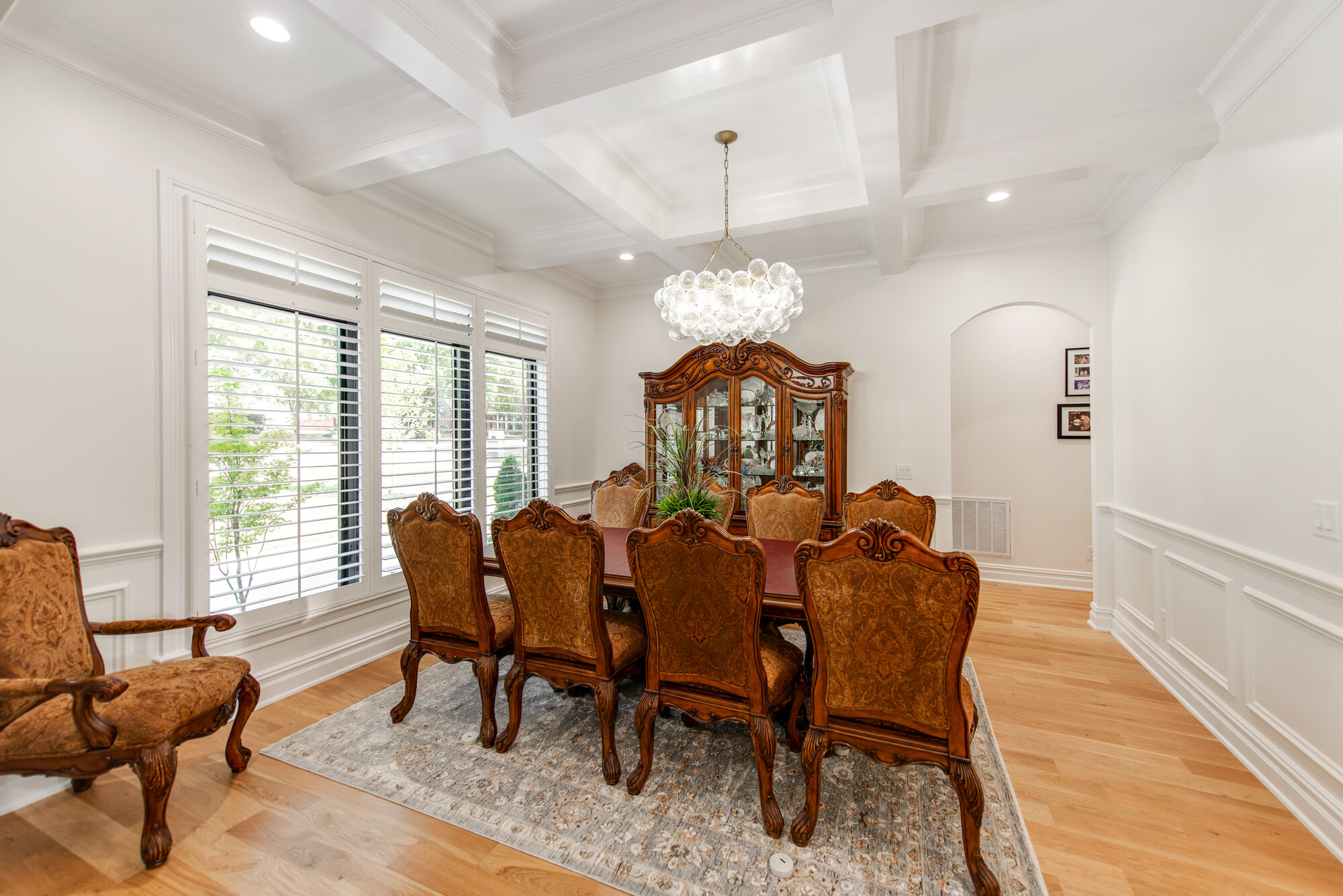 Formal dining room with coffered ceiling, capiz-shell chandelier, and plantation-shuttered window wall — Coddle Creek by Stillman Properties Concord NC