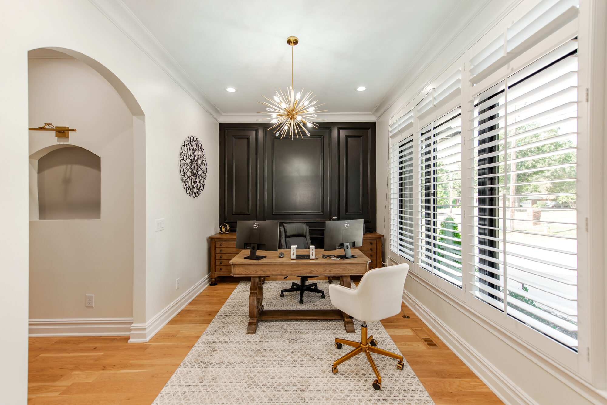 Private office with deep navy paneled feature wall, brass sputnik chandelier, and arched display niche — Coddle Creek by Stillman Properties Concord NC