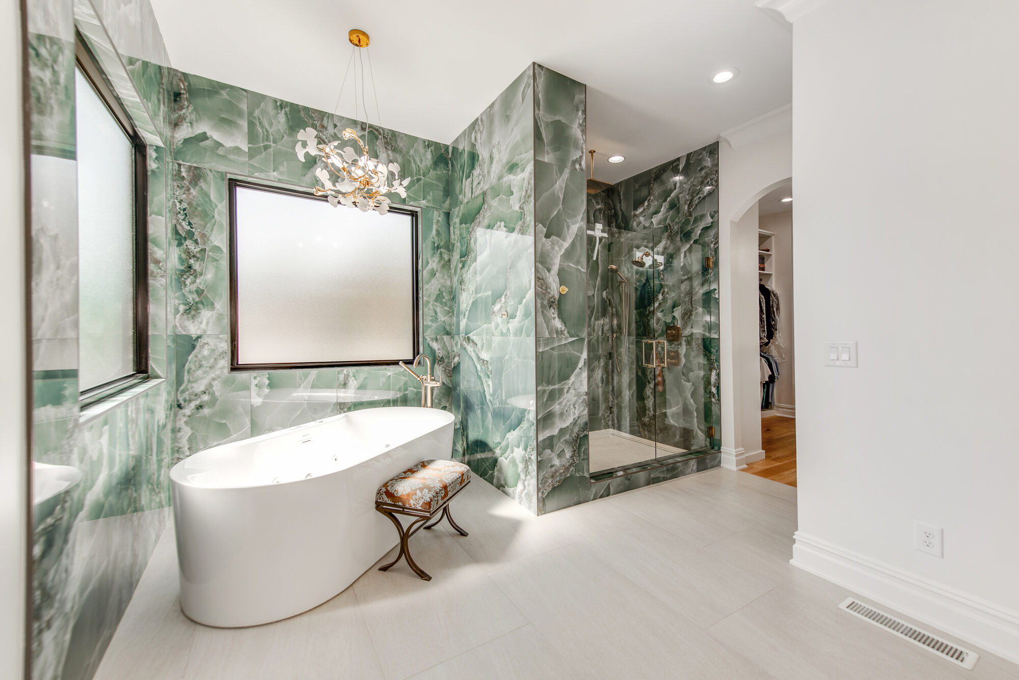 Green onyx primary bath with freestanding soaking tub, floral brass chandelier, and walk-in shower — Coddle Creek by Stillman Properties Concord NC