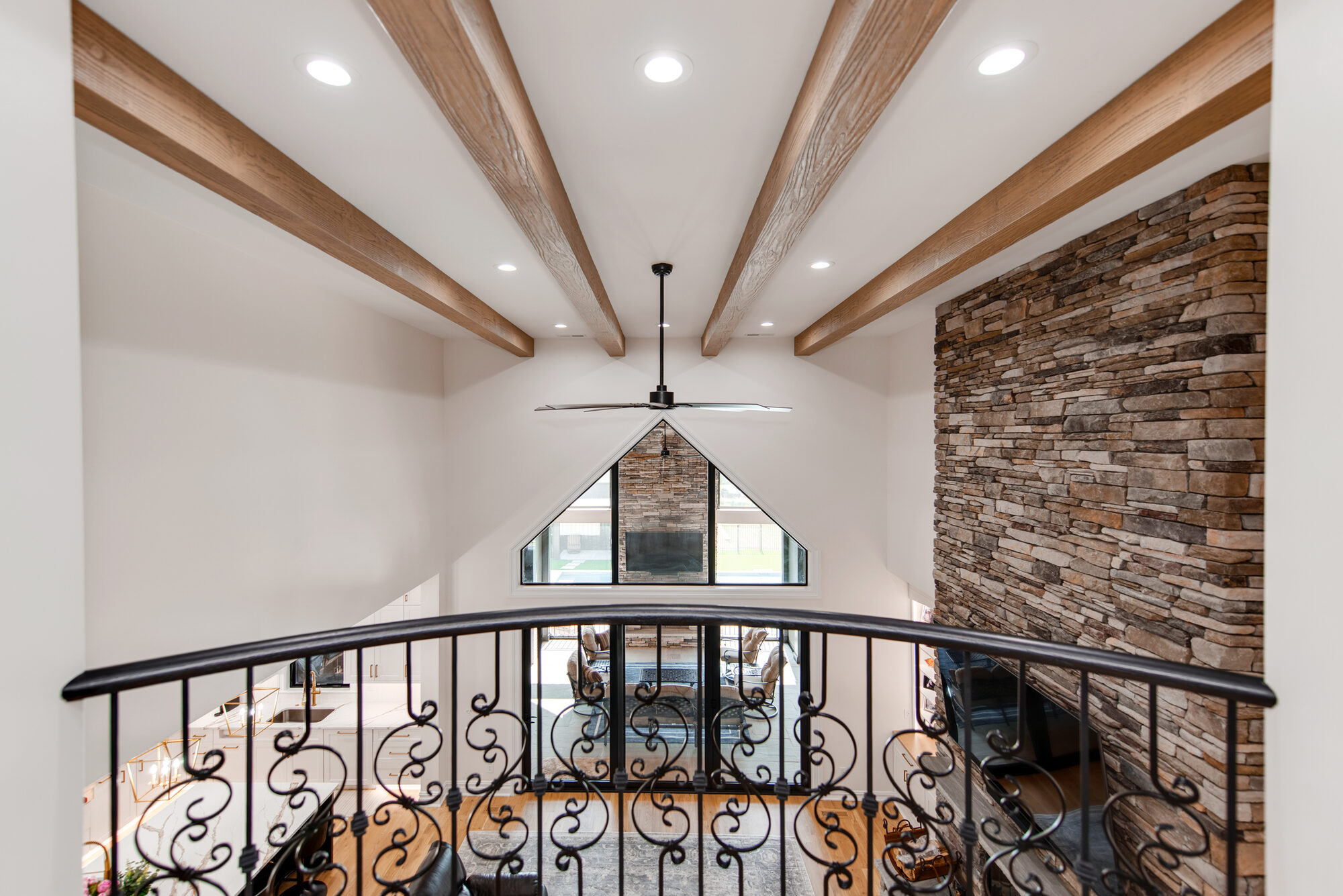 Juliet balcony at Coddle Creek with rough-hewn exposed beams overlooking the cathedral window wall and stone fireplace — Stillman Properties Concord NC