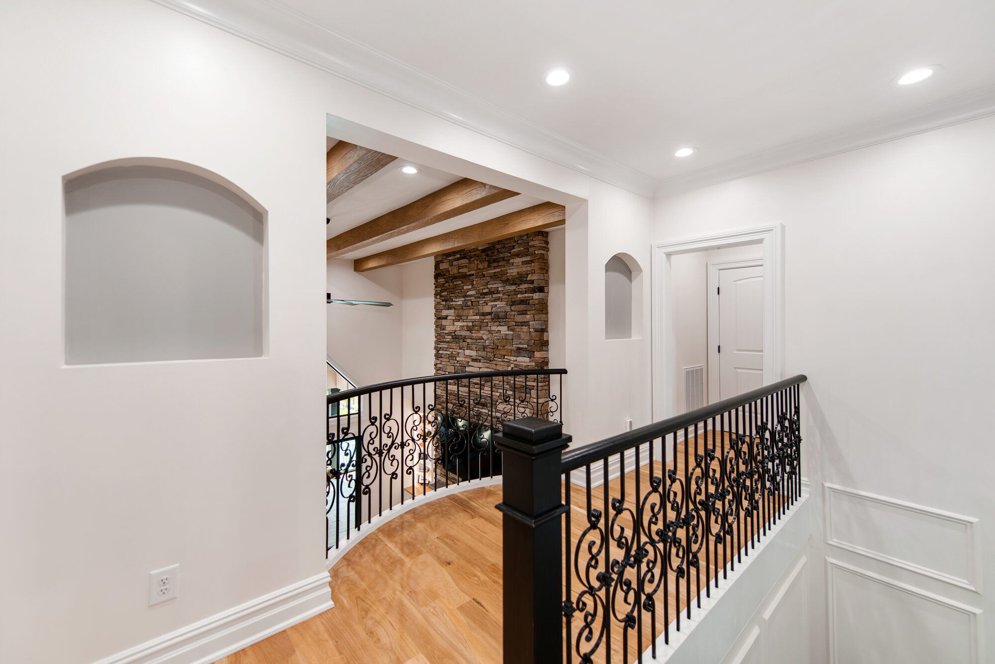 Upstairs hallway with arched display niches leading to the loft and stone feature wall — Coddle Creek by Stillman Properties Concord NC