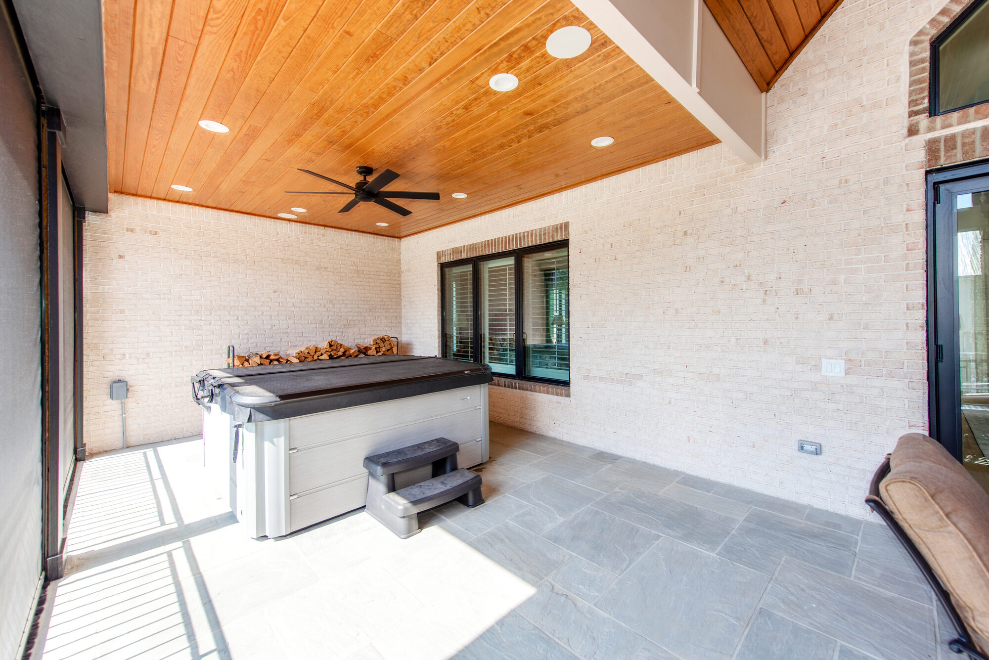 Covered hot tub area with cedar ceiling, brick walls, and integrated firewood storage — Coddle Creek by Stillman Properties Concord NC