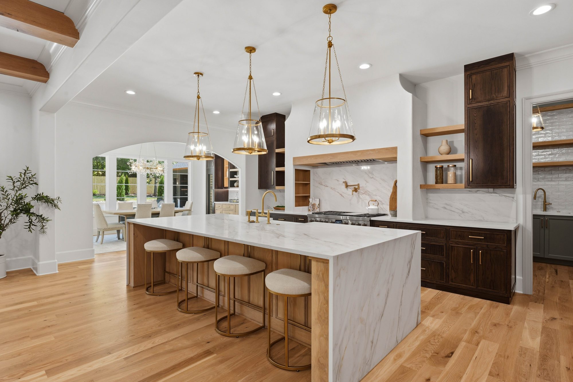 Chef's kitchen with waterfall calacatta island, brass pendants, and stained white oak cabinetry — Creola custom home in Charlotte NC by Stillman Properties