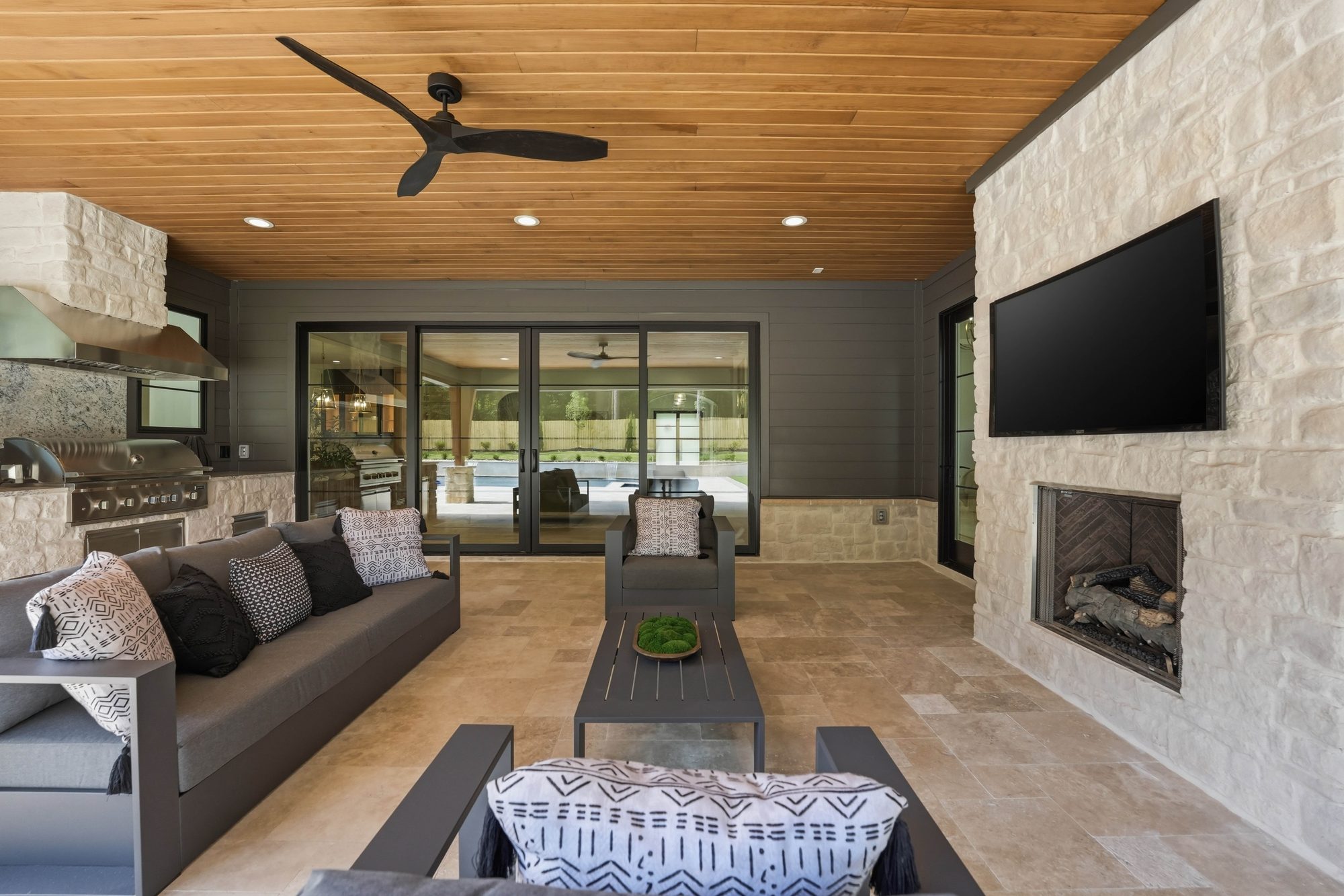 Covered outdoor living room during the day with fireplace and ceiling fans — Creola custom home in Charlotte NC by Stillman Properties