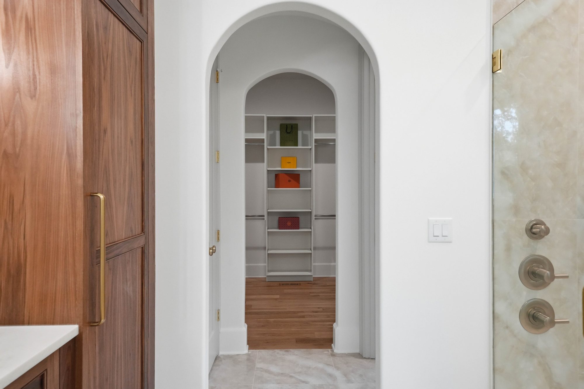 View through the primary bath's arched doorways to the custom walk-in closet — Creola custom home in Charlotte NC by Stillman Properties