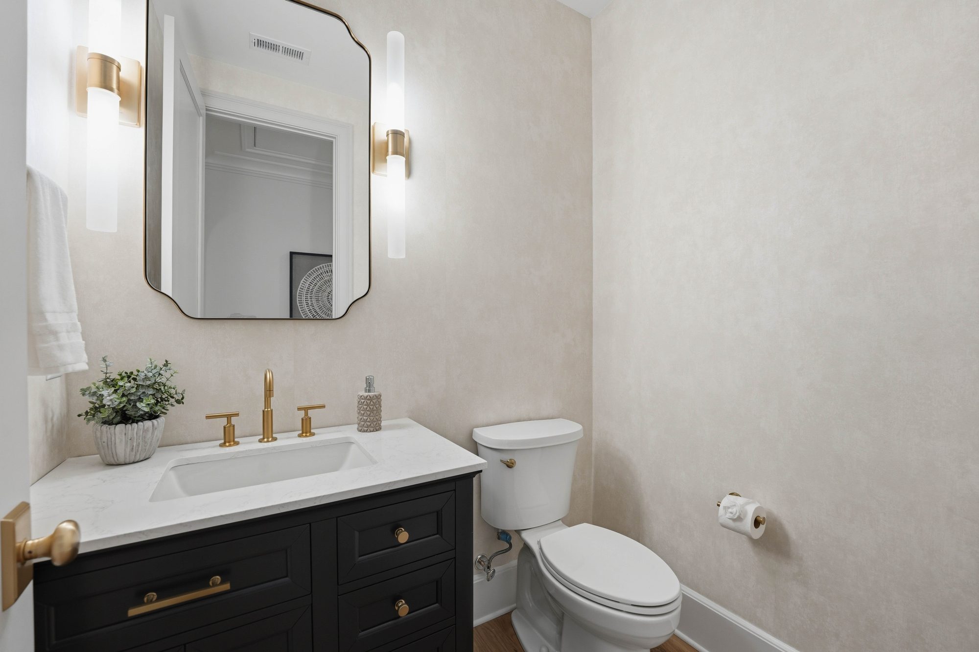Upper-level powder bath with parchment walls, black vanity, and brass sconces — Creola custom home in Charlotte NC by Stillman Properties