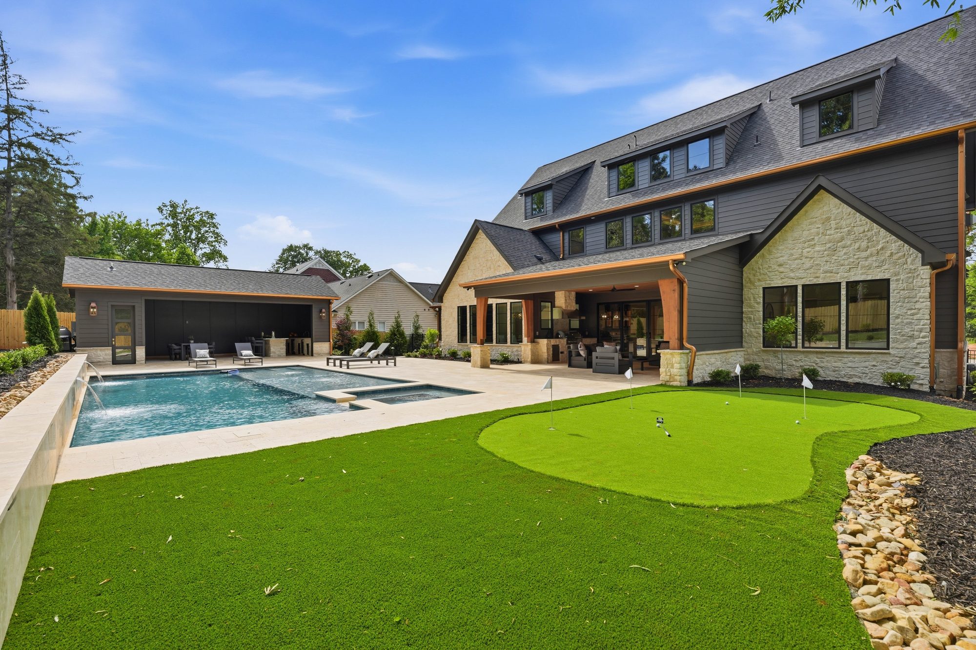 Wide property view showing the cabana, pool, putting green, and main house relationship — Creola custom home in Charlotte NC by Stillman Properties