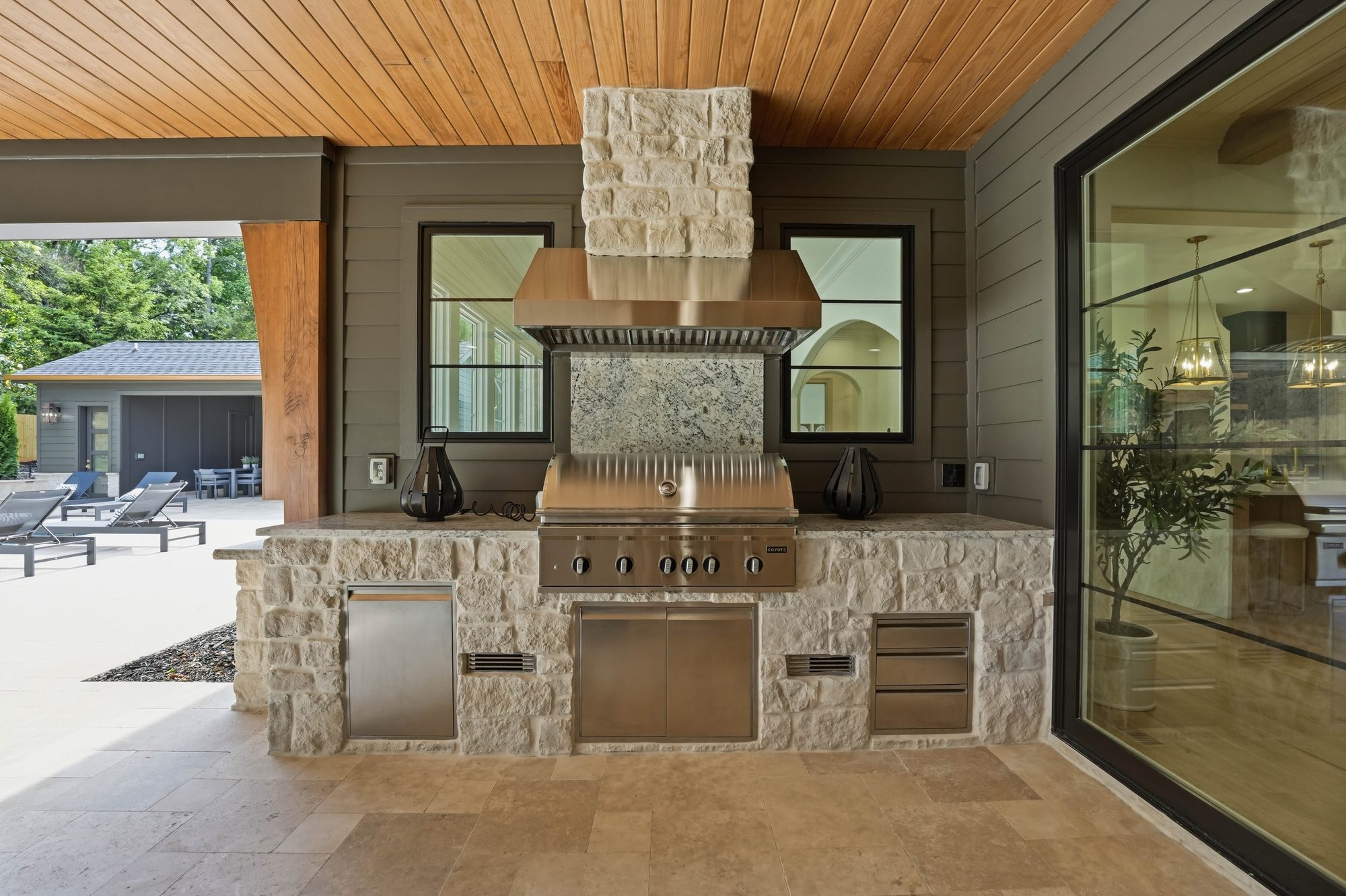Custom outdoor kitchen with copper hood, integrated grill, and stone surround beneath cedar ceiling — Creola custom home in Charlotte NC by Stillman Properties