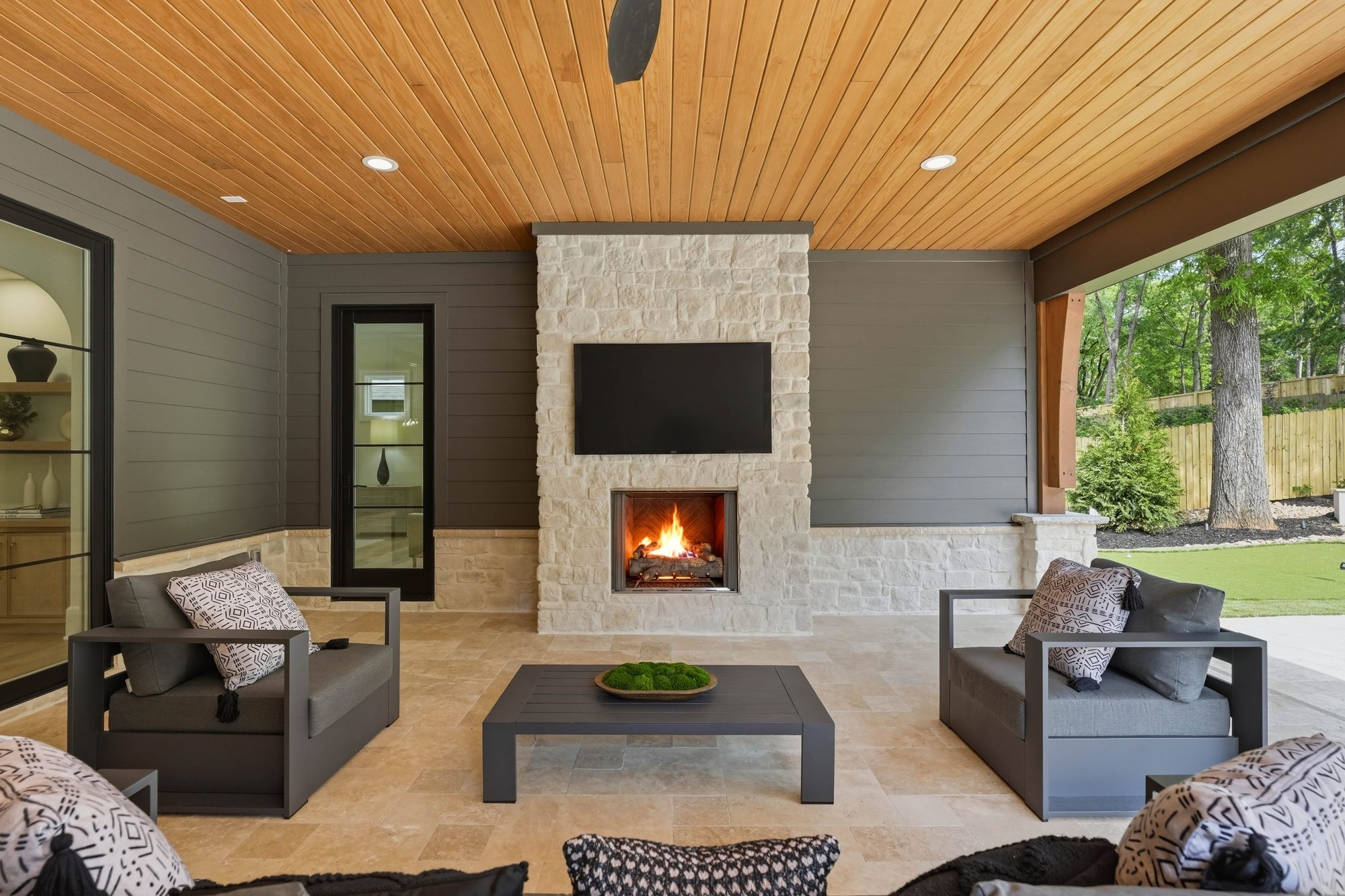 Stone fireplace and sectional in the covered outdoor living room — Creola custom home in Charlotte NC by Stillman Properties