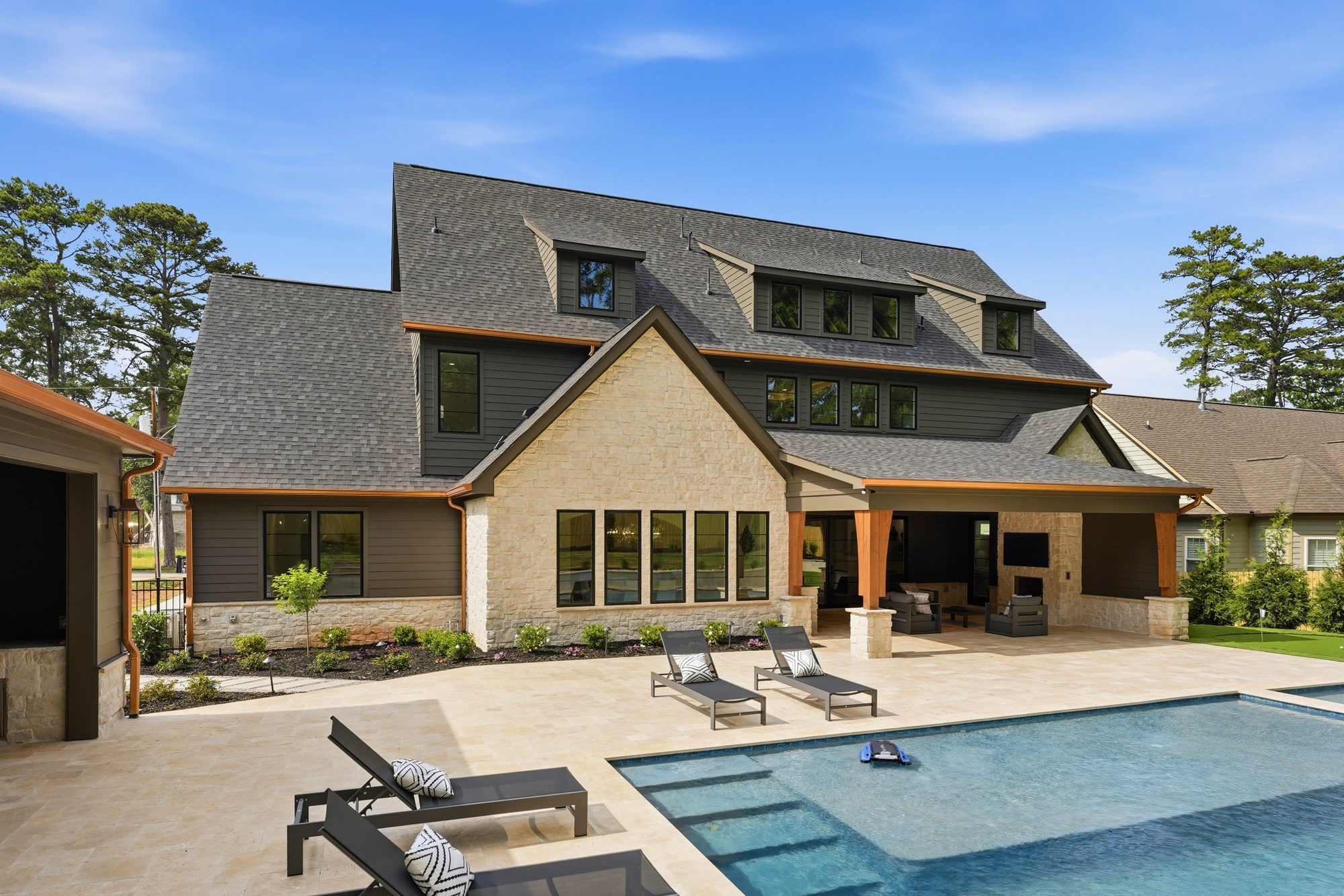 Rear view of Creola from the lawn with pool deck, chaise loungers, and architectural rear elevation — Creola custom home in Charlotte NC by Stillman Properties