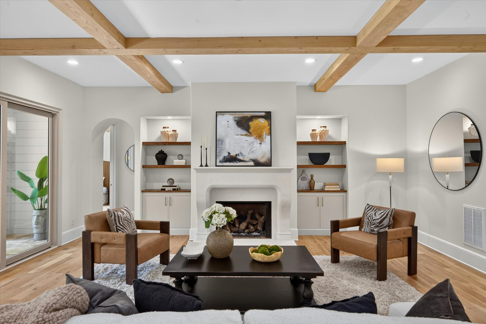 Great room at Heather with box-beam ceiling, cast stone fireplace, and flanking built-ins with walnut floating shelves — Heather by Stillman Properties Charlotte NC