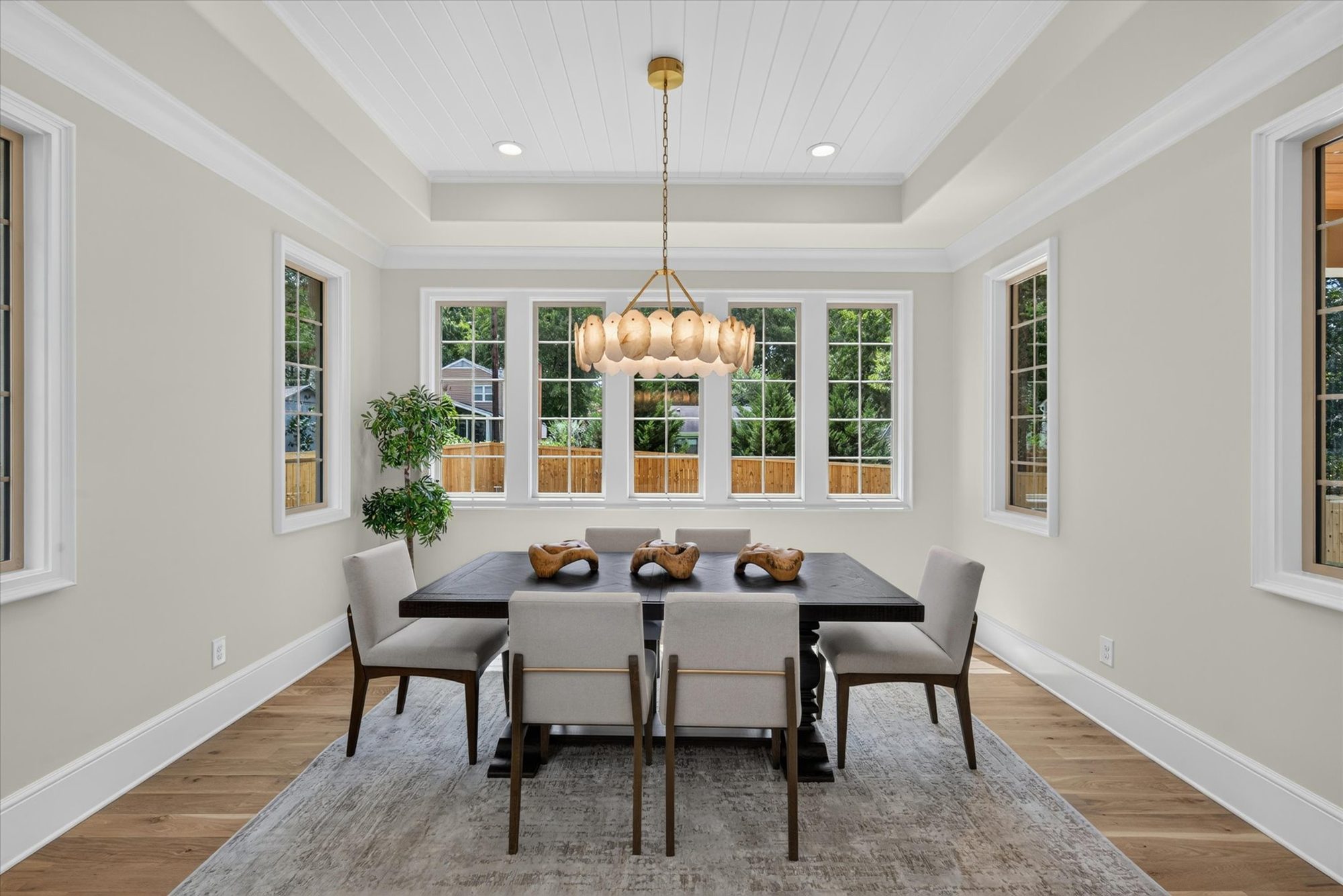 Dining room at Heather with shiplap tray ceiling, alabaster disc chandelier, and a wall of divided-light windows — Heather by Stillman Properties Charlotte NC