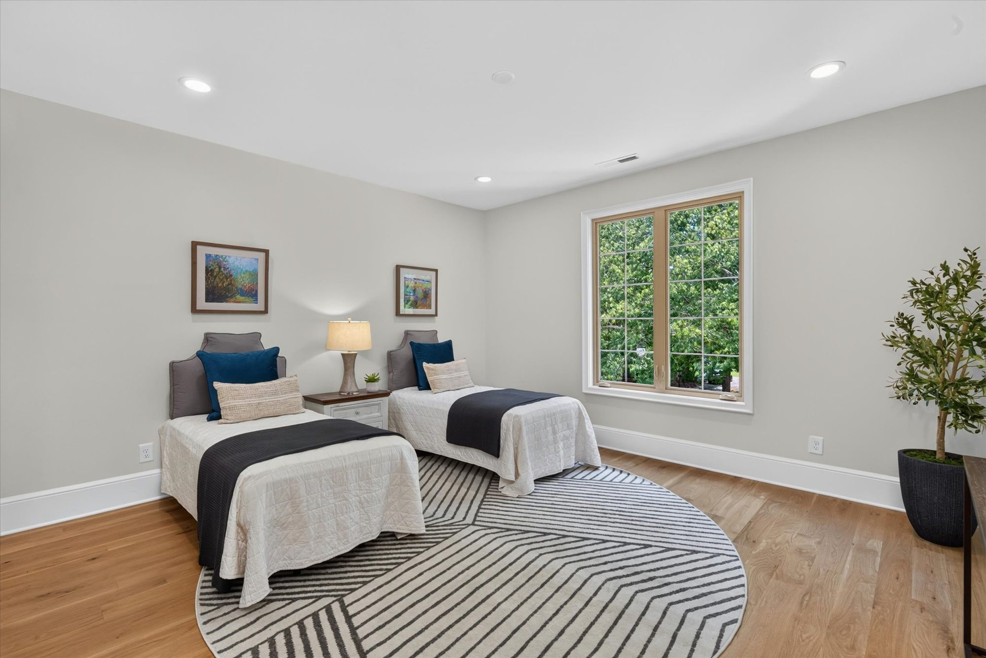 Upper-level bedroom at Heather with twin beds, white oak floors, and a divided-light window overlooking the trees — Heather by Stillman Properties Charlotte NC