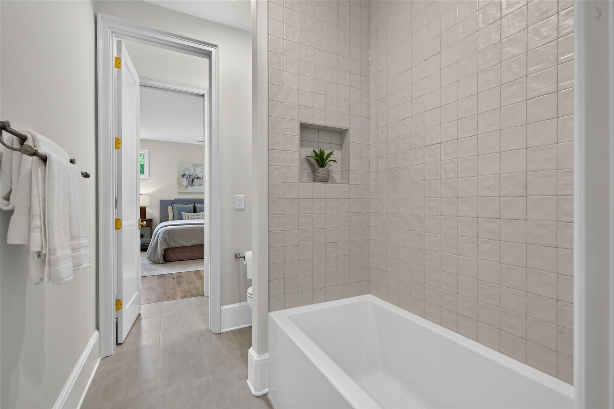 Tub-shower at Heather in stacked glazed square tile with recessed niche, opening to the adjacent bedroom — Heather by Stillman Properties Charlotte NC