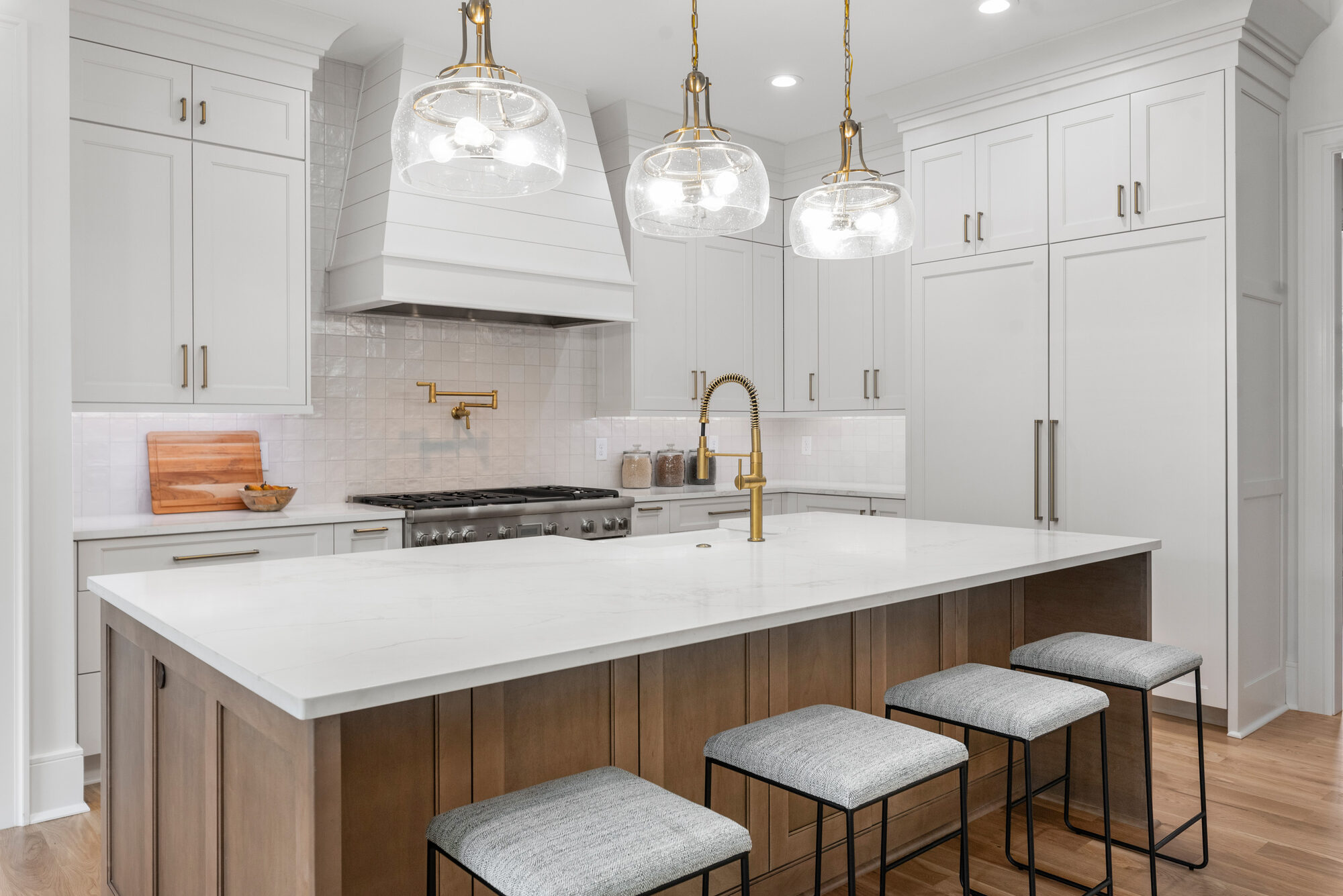 Walker chef's kitchen with walnut island, white quartz waterfall, shiplap range hood, and brass-and-glass pendant lighting — Stillman Properties Cotswold Charlotte NC