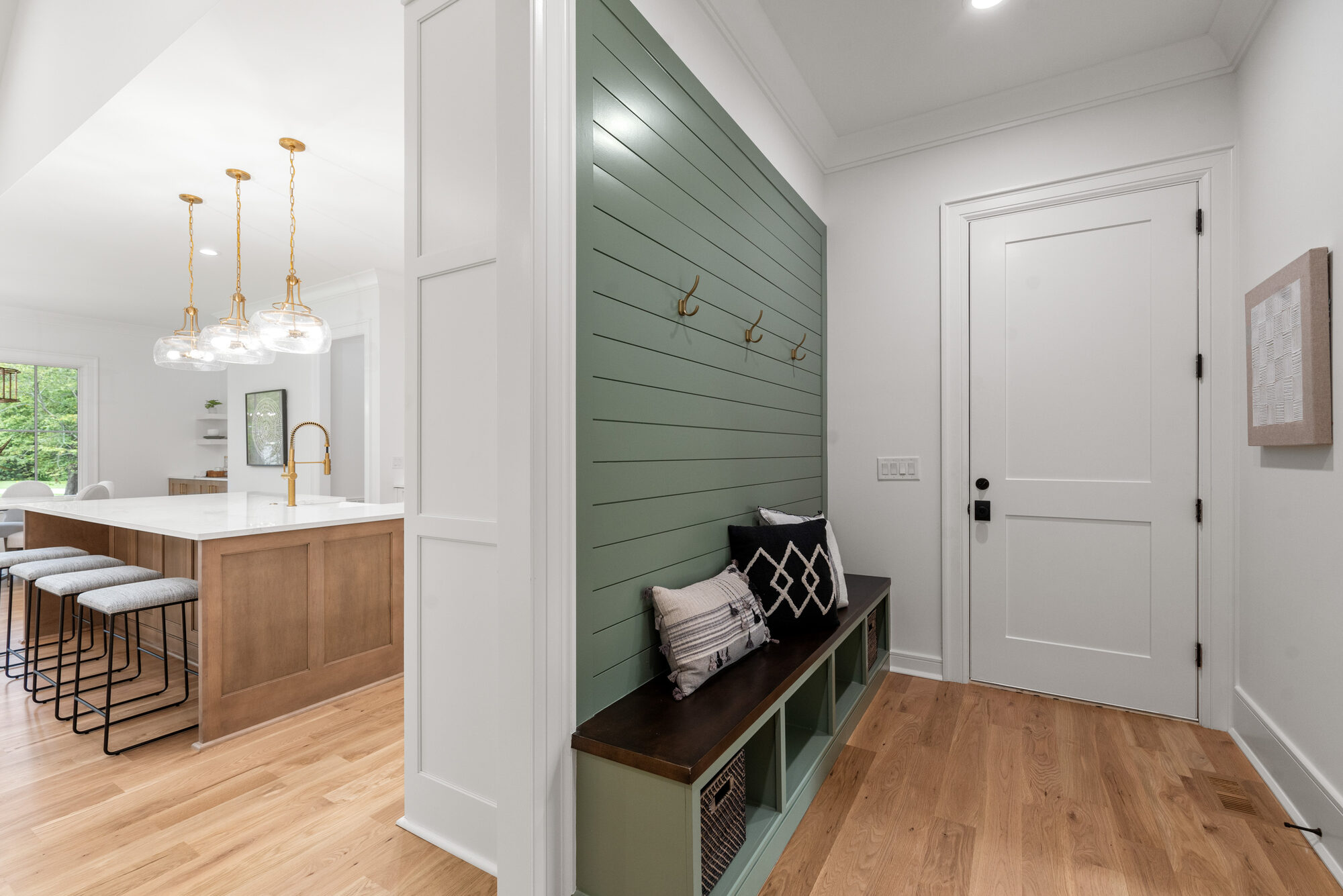 Walker mudroom with sage green shiplap, brass coat hooks, and built-in bench with cubbies — Stillman Properties Cotswold Charlotte NC