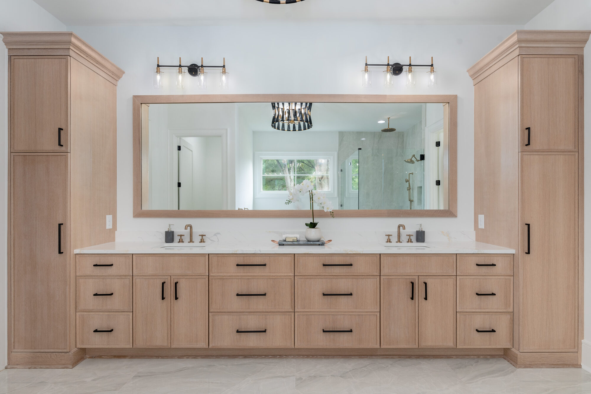 Walker primary spa bath with symmetrical white oak vanity, brass fixtures, and flanking linen towers — Stillman Properties Cotswold Charlotte NC