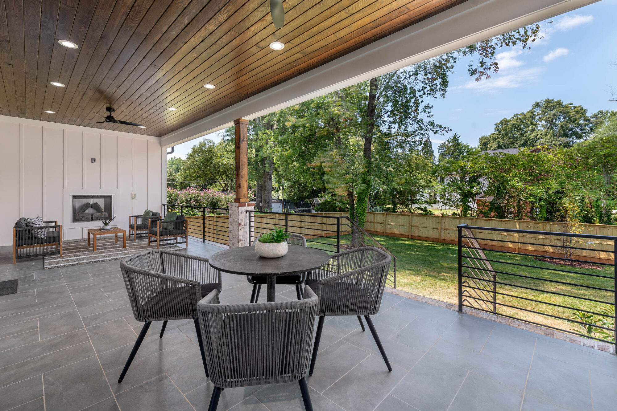 Walker covered rear deck with stained tongue-and-groove ceiling, outdoor fireplace, and view to the fenced yard — Stillman Properties Cotswold Charlotte NC