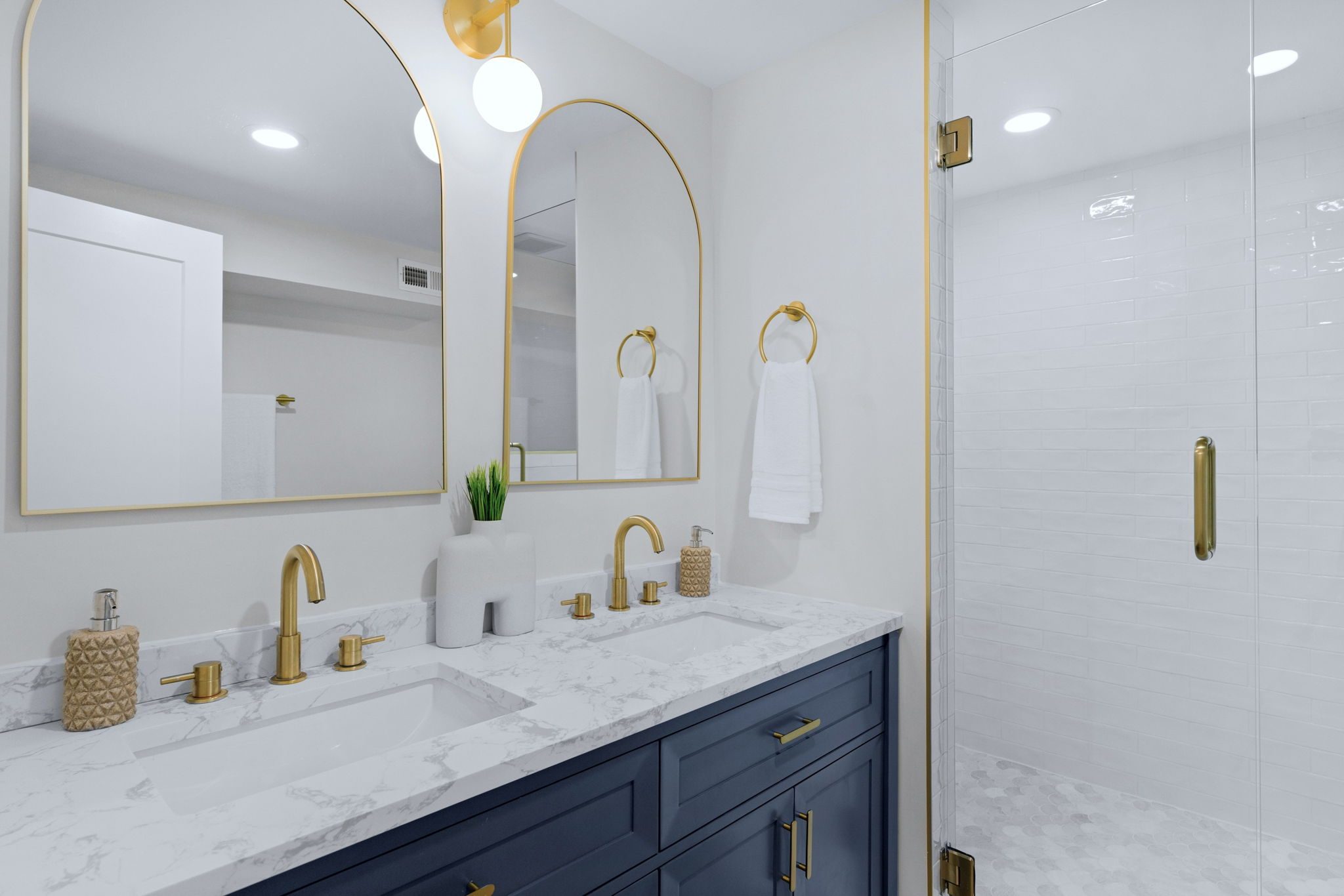 Lower-level full bath with navy vanity, marble-look counter, and gold fixtures — Wyanoke by Stillman Properties Charlotte NC